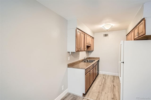 kitchen with freestanding refrigerator, a sink, light wood-type flooring, and baseboards