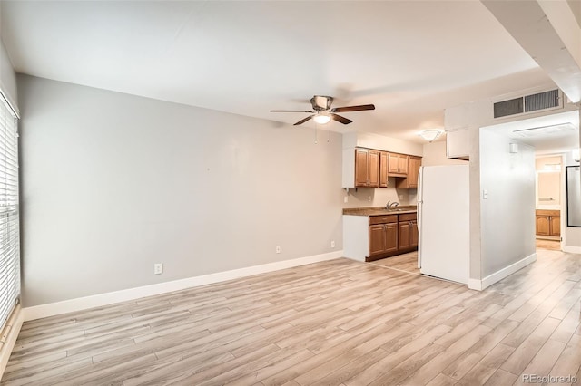 unfurnished living room featuring a ceiling fan, baseboards, and light wood-type flooring