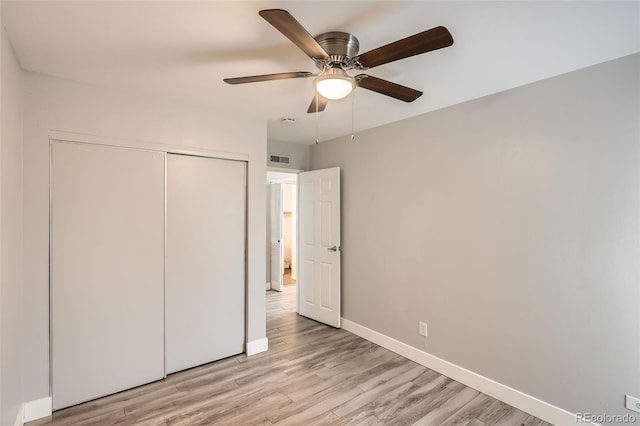 unfurnished bedroom with baseboards, light wood-style floors, a closet, and ceiling fan