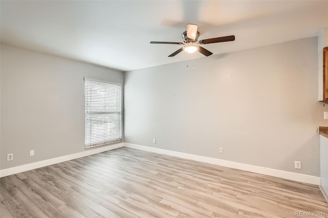 spare room featuring ceiling fan, light wood-type flooring, and baseboards