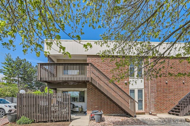 rear view of property featuring stairs, fence, and brick siding