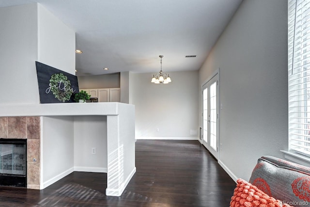 interior space with dark hardwood / wood-style flooring, a tile fireplace, and a notable chandelier