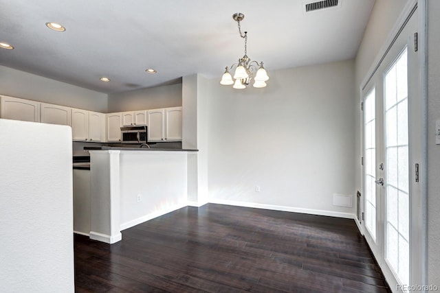 kitchen with decorative light fixtures, a chandelier, dark hardwood / wood-style flooring, kitchen peninsula, and white cabinets