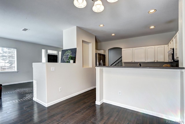 kitchen featuring stainless steel appliances, white cabinets, dark hardwood / wood-style flooring, and kitchen peninsula