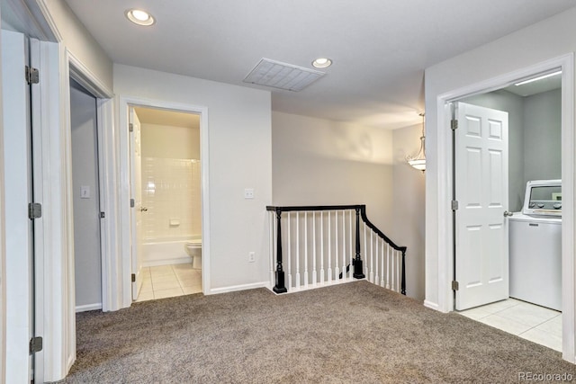 corridor with washer / dryer and light carpet