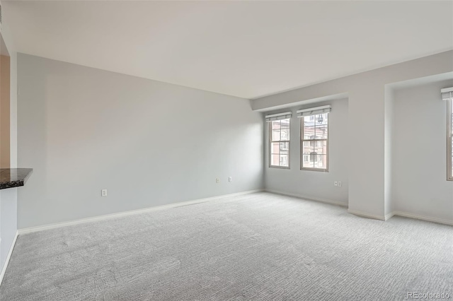 unfurnished room with light colored carpet and baseboards