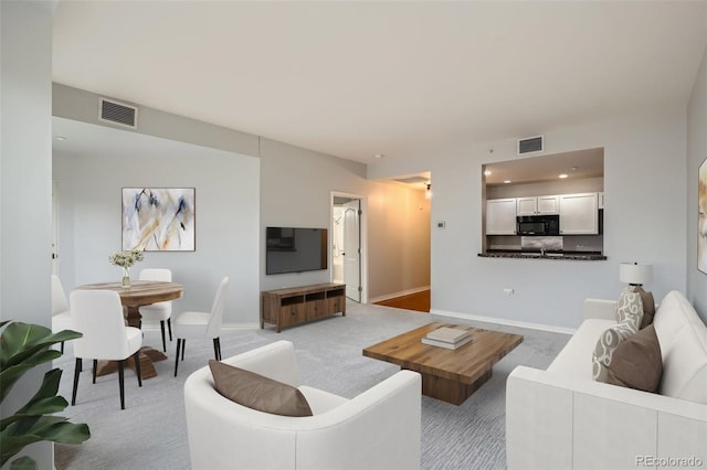 living room featuring light carpet, baseboards, and recessed lighting
