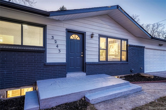 property entrance with a garage and brick siding