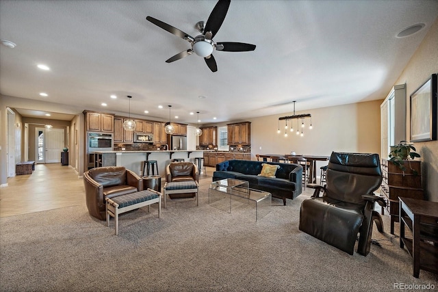 living room featuring ceiling fan with notable chandelier and light carpet