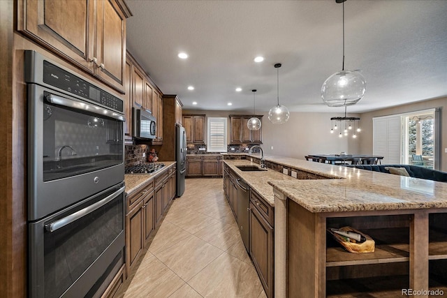 kitchen with decorative backsplash, stainless steel appliances, a spacious island, sink, and hanging light fixtures