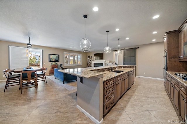 kitchen with a barn door, sink, pendant lighting, and a large island with sink