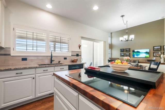 9005 Royal Melbourne Cir, Peyton, CO 80831 - kitchen with butcher block countertops, a chandelier, tasteful backsplash, white cabinets, and dark wood-type flooring