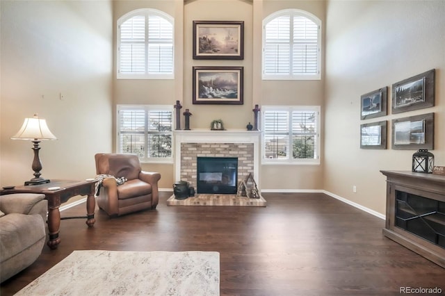 9005 Royal Melbourne Cir, Peyton, CO 80831 - living room featuring a towering ceiling, a fireplace, dark wood-style floors, and healthy amount of natural light