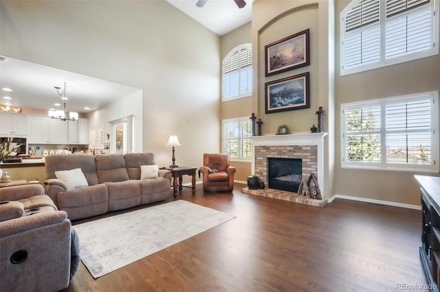 9005 Royal Melbourne Cir, Peyton, CO 80831 - living room with a high ceiling, plenty of natural light, a brick fireplace, and dark wood-style flooring