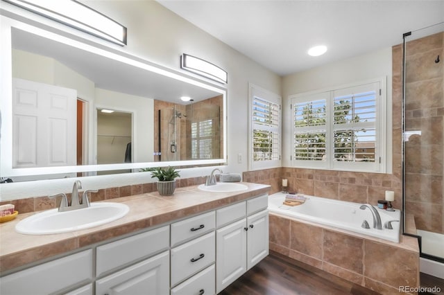 9005 Royal Melbourne Cir, Peyton, CO 80831 - full bathroom with wood finished floors, double vanity, a tile shower, a bath, and a spacious closet