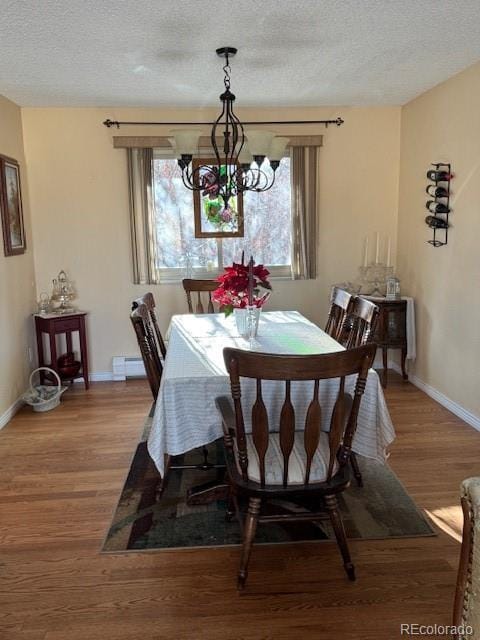 dining room with hardwood / wood-style flooring, an inviting chandelier, baseboard heating, and a textured ceiling