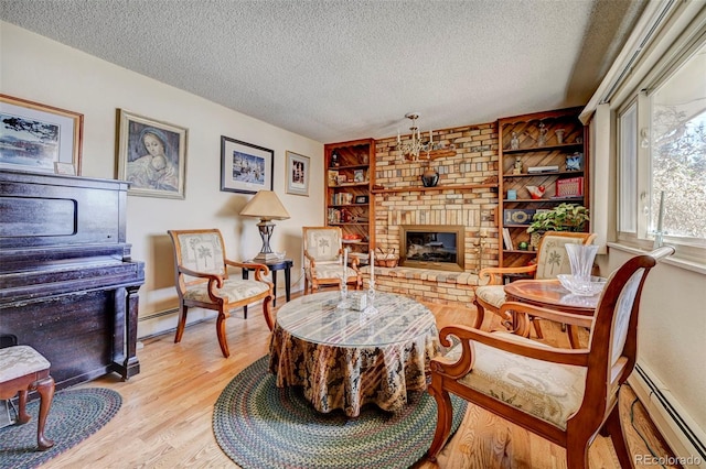 sitting room featuring light hardwood / wood-style flooring, a fireplace, a baseboard radiator, and a textured ceiling