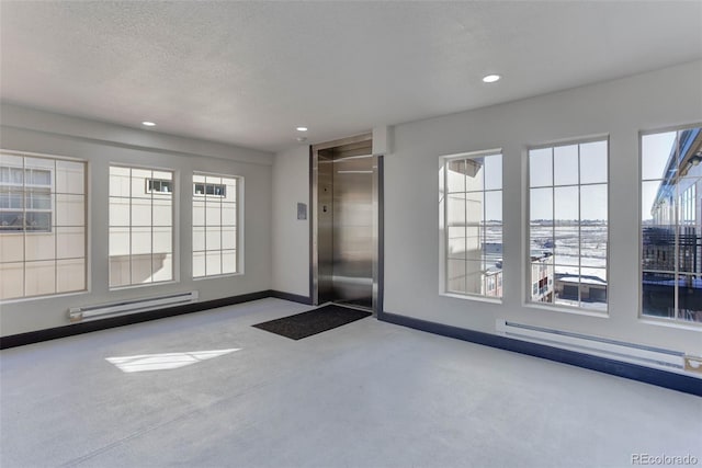 interior space with baseboard heating, elevator, and a textured ceiling