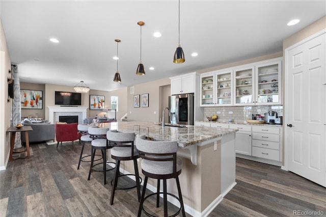 kitchen featuring stainless steel fridge, a fireplace, dark wood-style flooring, white cabinetry, and recessed lighting