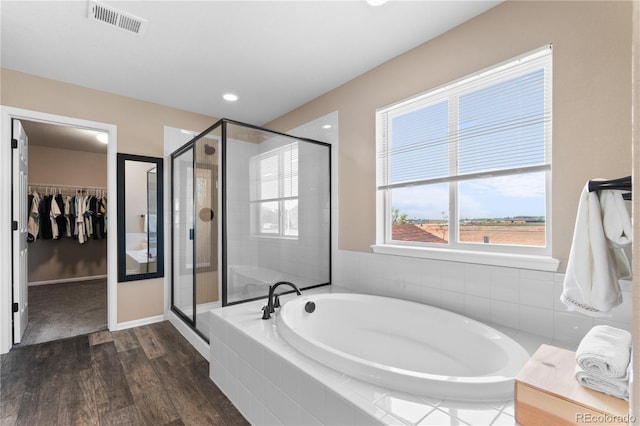 bathroom with wood finished floors, a shower stall, a bath, and a walk in closet