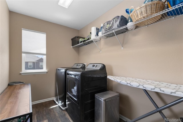 clothes washing area with dark wood finished floors, washing machine and clothes dryer, and baseboards