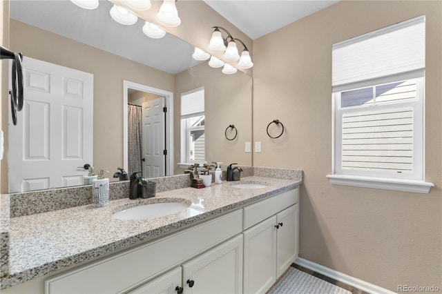 bathroom with double vanity and baseboards