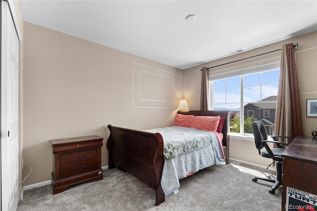 carpeted bedroom with an office area and baseboards