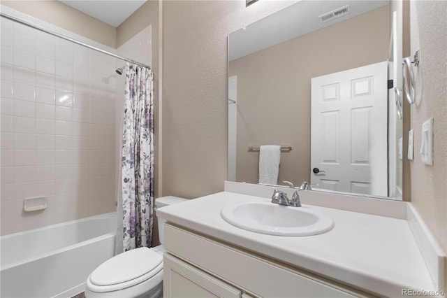 full bath with toilet, shower / bath combo, vanity, and a textured wall