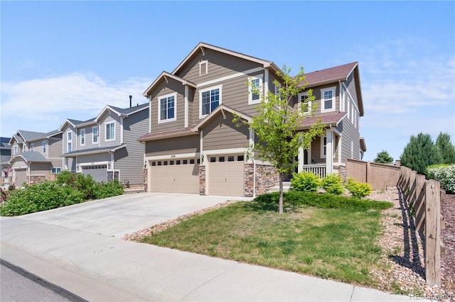 craftsman-style home featuring a garage, concrete driveway, a residential view, and stone siding