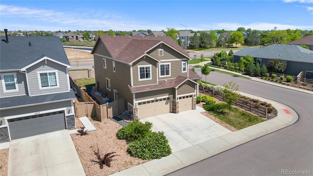 craftsman house featuring an attached garage, driveway, a residential view, and stone siding