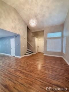 6973 Summerset Ave, Longmont, CO 80504 - unfurnished living room with high vaulted ceiling, baseboards, wood finished floors, and stairway