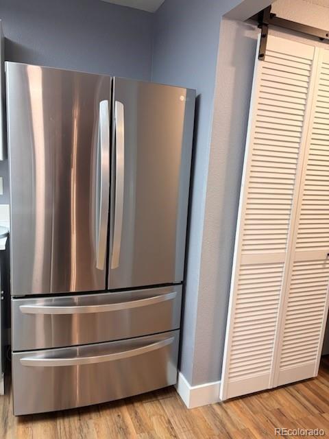 6973 Summerset Ave, Longmont, CO 80504 - detailed view of freestanding refrigerator, light wood-style flooring, a barn door, and baseboards