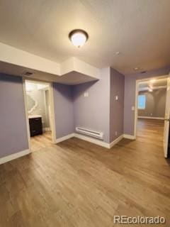 6973 Summerset Ave, Longmont, CO 80504 - finished basement featuring a baseboard radiator, wood finished floors, and baseboards