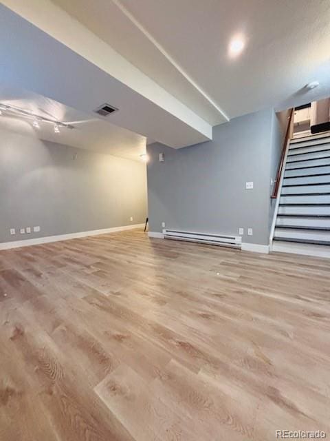 6973 Summerset Ave, Longmont, CO 80504 - finished basement featuring a baseboard heating unit, baseboards, stairway, and light wood-style flooring