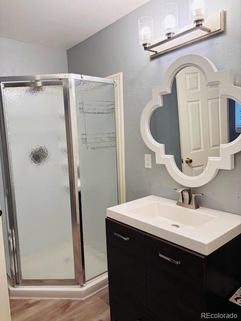 6973 Summerset Ave, Longmont, CO 80504 - bathroom featuring wood finished floors, vanity, and a stall shower
