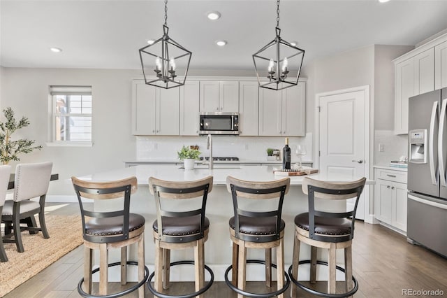15608 E Otero Cir, Centennial, CO 80112 - kitchen with stainless steel appliances, a chandelier, recessed lighting, an island with sink, and light countertops
