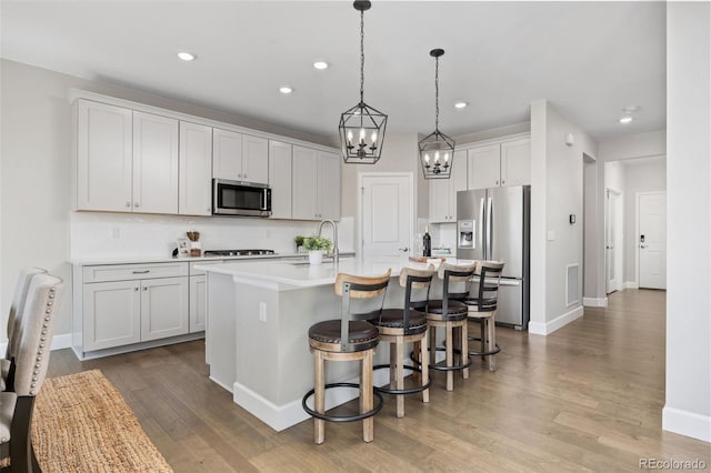 15608 E Otero Cir, Centennial, CO 80112 - kitchen featuring stainless steel appliances, a sink, wood finished floors, an island with sink, and recessed lighting