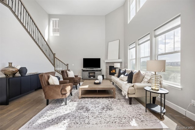 15608 E Otero Cir, Centennial, CO 80112 - living room with wood finished floors, healthy amount of natural light, a towering ceiling, a glass covered fireplace, and baseboards