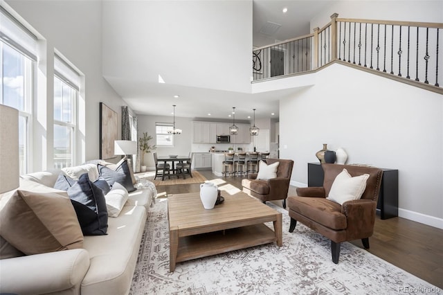 15608 E Otero Cir, Centennial, CO 80112 - living area featuring light wood-style floors, a towering ceiling, a chandelier, and baseboards