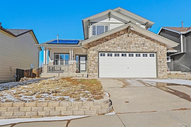 view of front of home with a porch, a garage, and solar panels