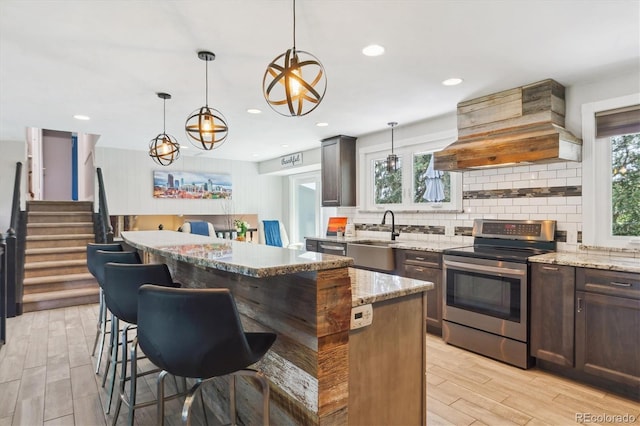6537 S Brentwood Way, Littleton, CO 80123 - kitchen with stainless steel electric range, a sink, premium range hood, a kitchen island, and tasteful backsplash