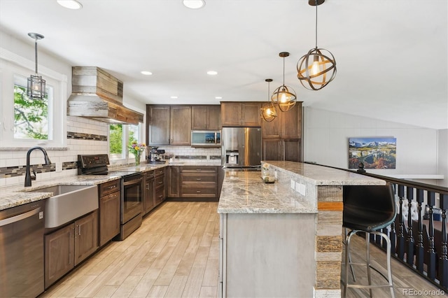 6537 S Brentwood Way, Littleton, CO 80123 - kitchen with stainless steel appliances, a sink, a center island, custom range hood, and light wood-style flooring