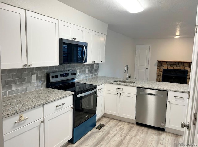 kitchen with tasteful backsplash, electric range, stainless steel dishwasher, light wood-style floors, and a sink