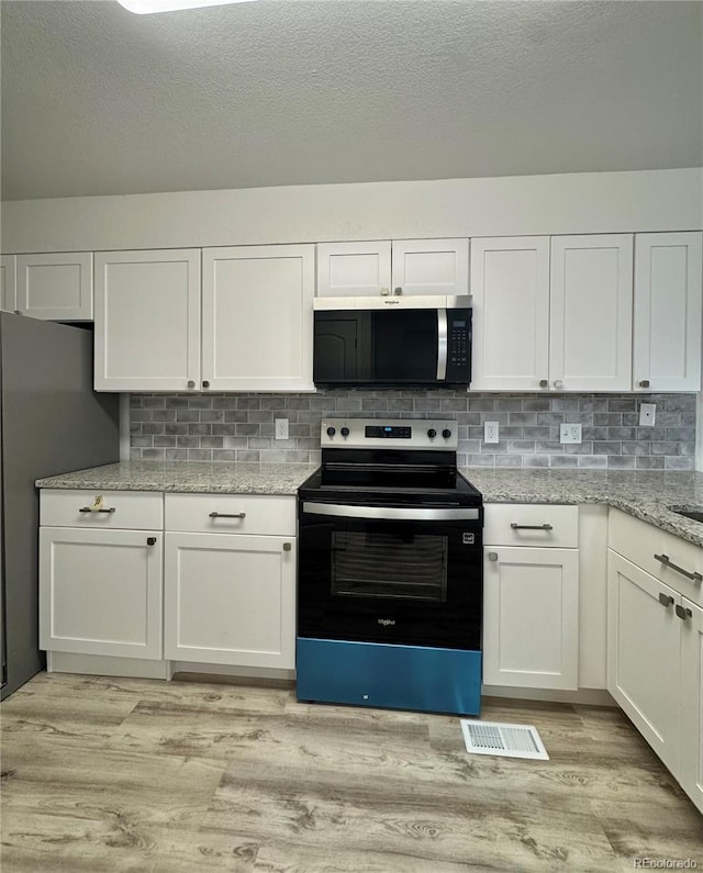 kitchen featuring stainless steel appliances, white cabinets, and light wood-style floors