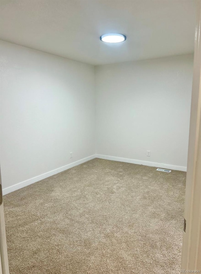 spare room featuring carpet, visible vents, and baseboards