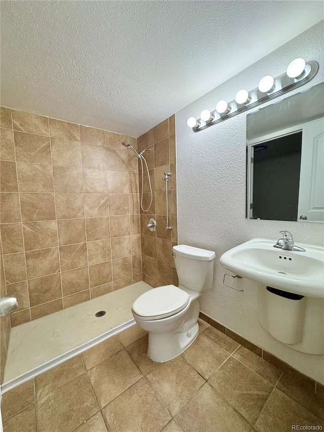 full bath featuring toilet, a textured ceiling, tiled shower, and tile patterned floors