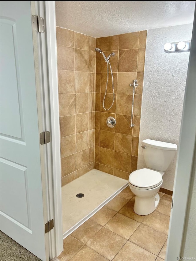 bathroom featuring a textured ceiling, tiled shower, and toilet