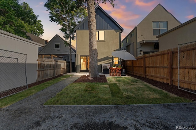 3363 W 32nd Ave, Denver, CO 80211 - back of property at dusk featuring a fenced backyard, a patio, and board and batten siding
