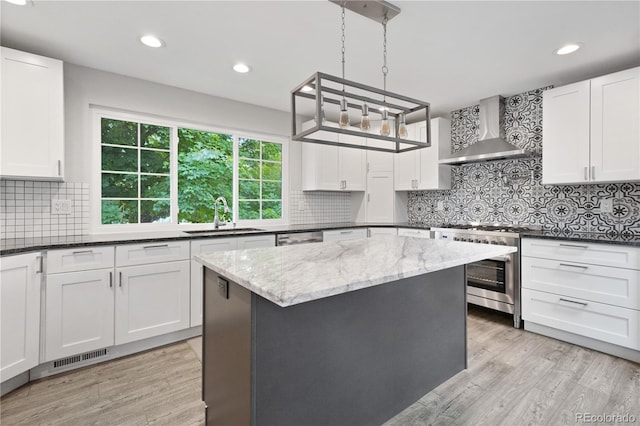 6451 S Hoyt St, Littleton, CO 80123 - kitchen with high end stainless steel range oven, wall chimney range hood, dark stone counters, backsplash, and white cabinetry