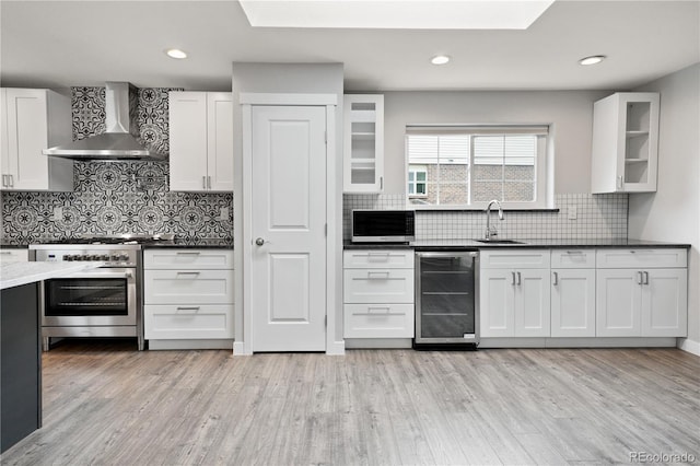 6451 S Hoyt St, Littleton, CO 80123 - kitchen featuring high end stove, wall chimney exhaust hood, wine cooler, backsplash, and white cabinets